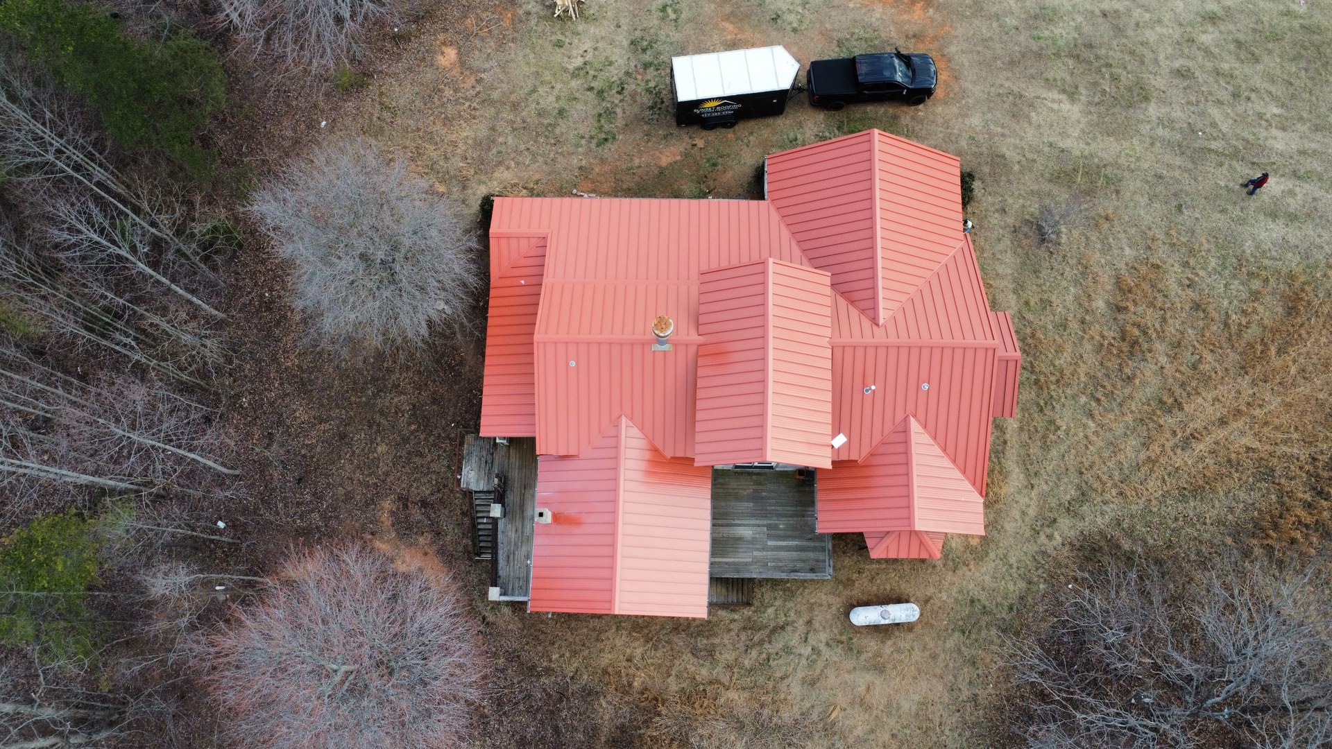 Aerial view of a red metal roof on a home published in Sunset Roofing and Construction's project gallery