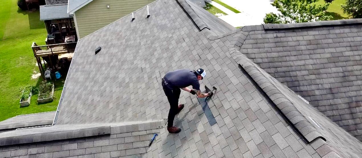 Roofer installing shingles on a residential roof