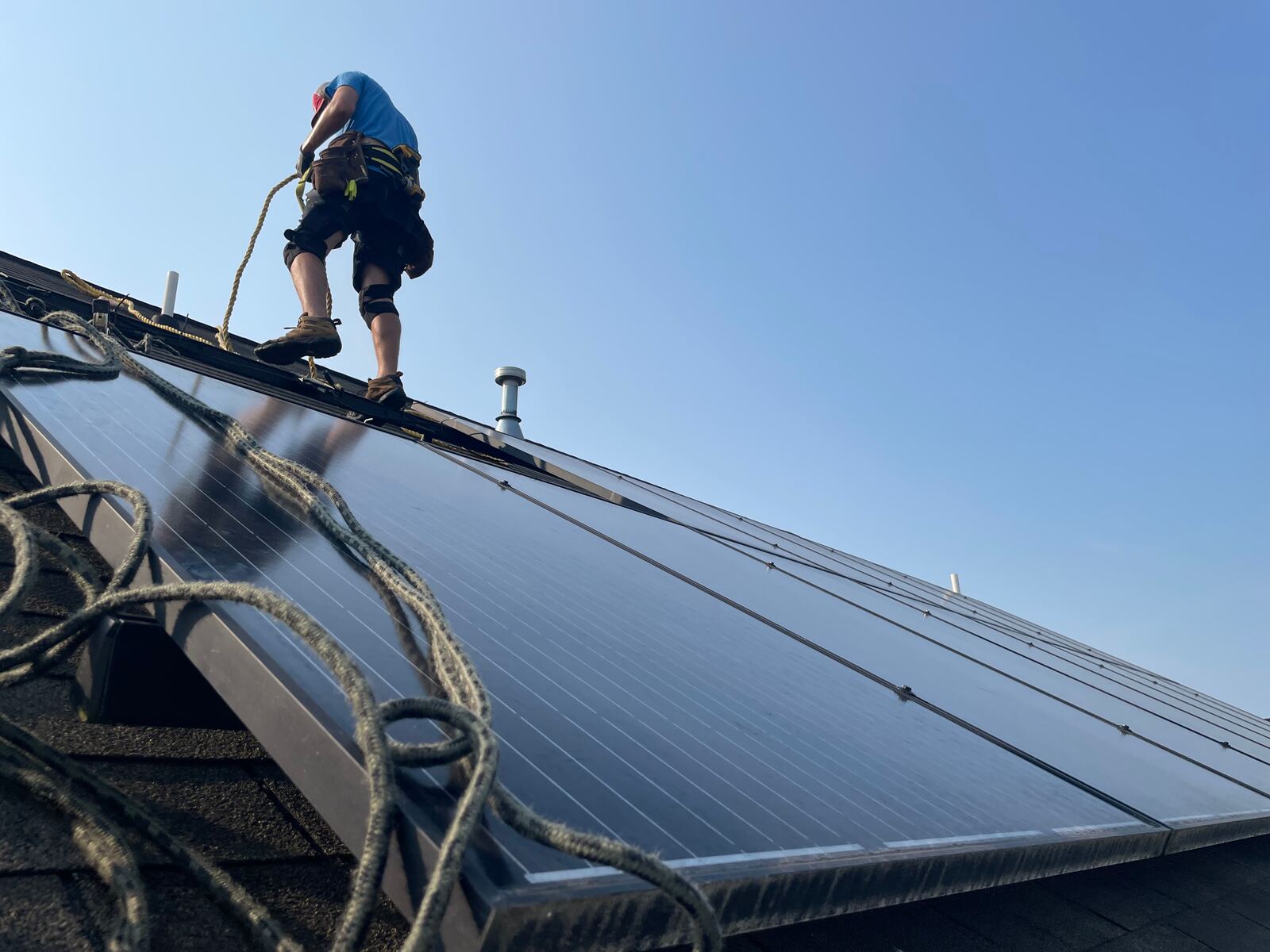 Roofer working beside solar panels on a residential roof
